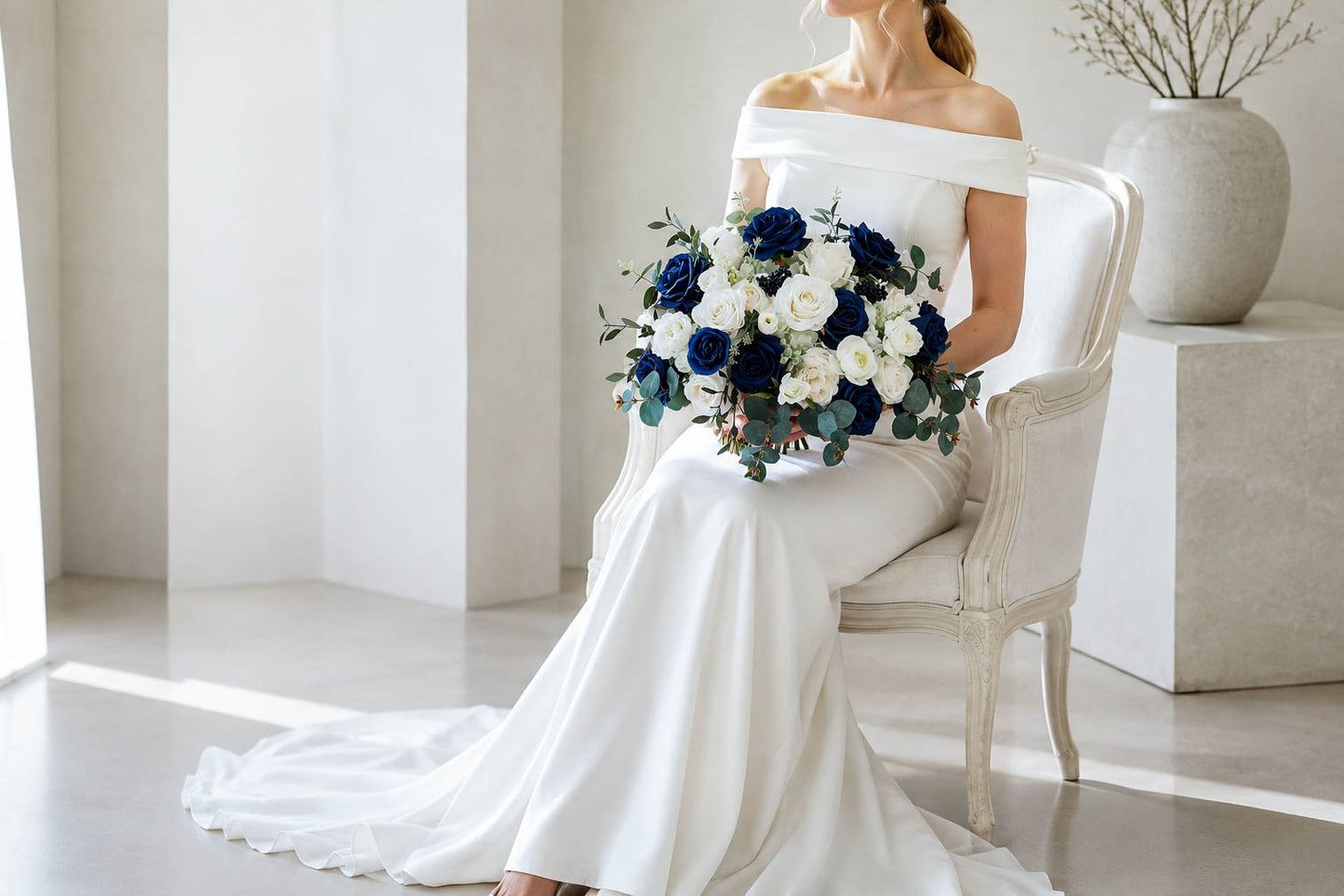 Seated bride holding navy blue and white artificial wedding bouquet with eucalyptus